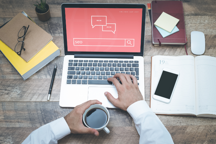 A desk with a laptop, notebooks, and a coffee cup.