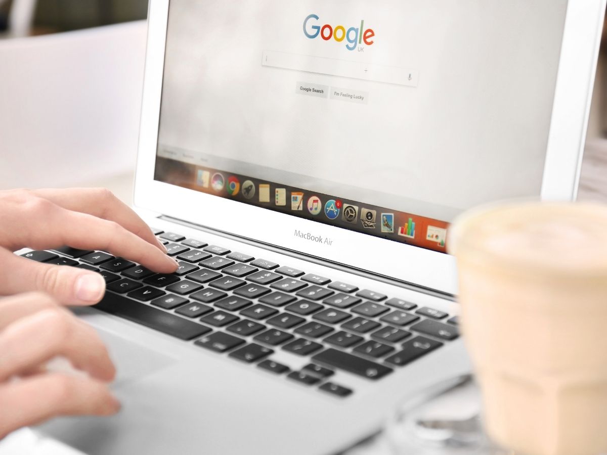 Person typing on Macbook Air laptop on Google search